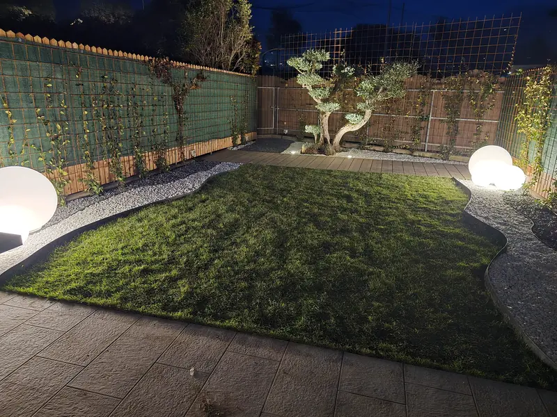 Giardino di notte con prato, ghiaia bianca, sfere luminose e albero a bonsai